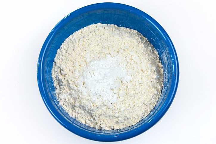 Flour, baking soda, baking powder, and a pinch of salt in a bowl.