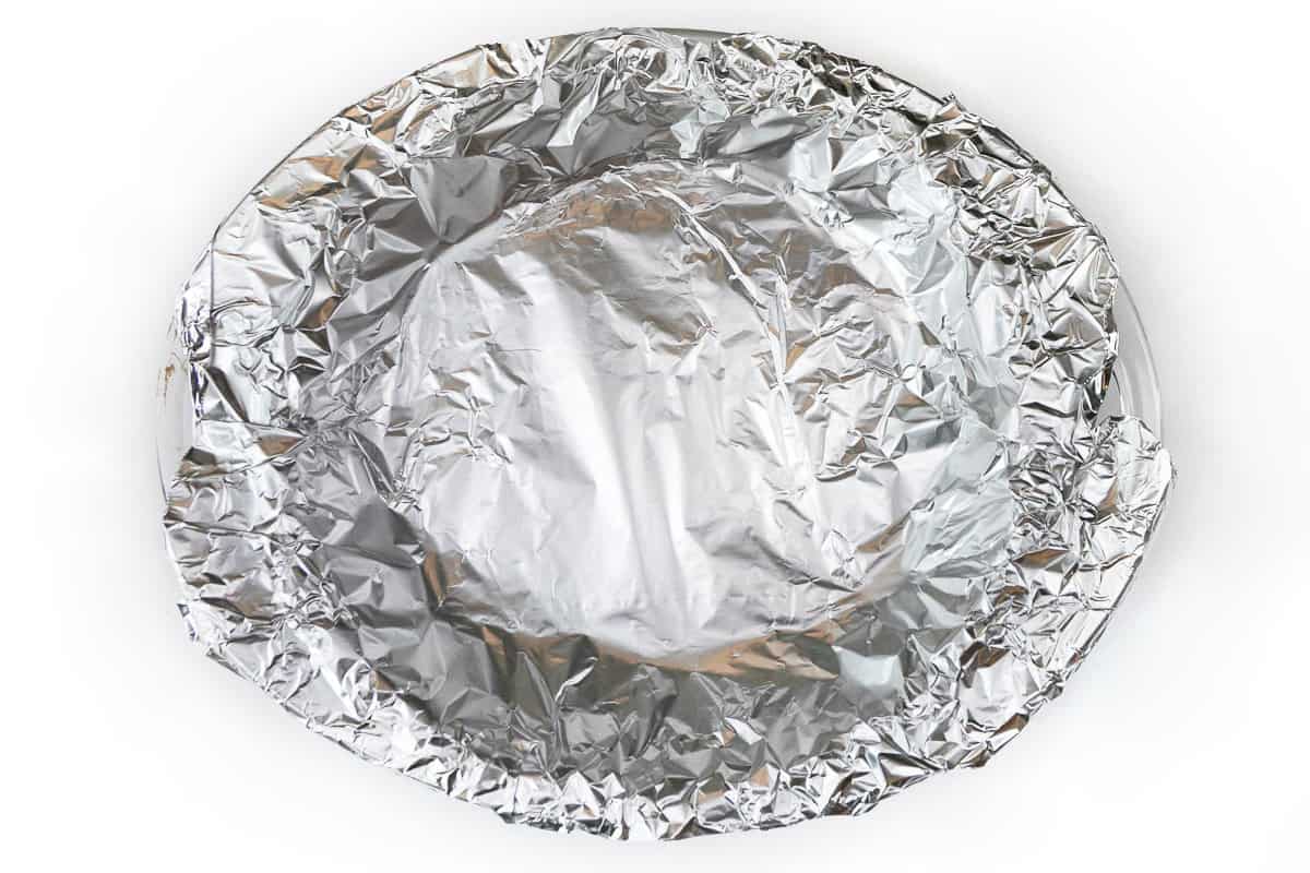 Aluminum foil is covering the pie dough.
