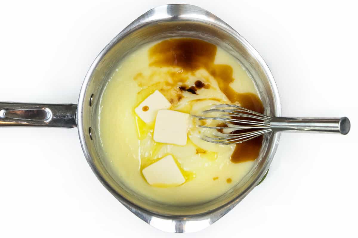 Vanilla extract and unsalted butter are added to the thickened cream mixture.