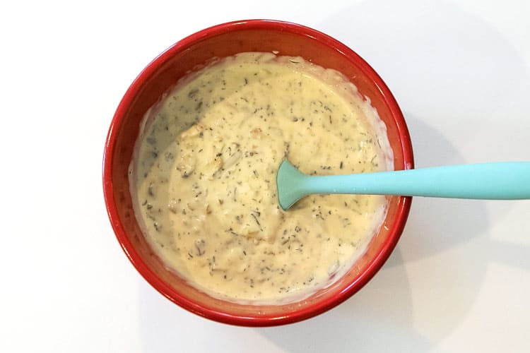 Mayonnaise, sweet relish, diced onions, yellow mustard, and parsley flakes blended together in a bowl.