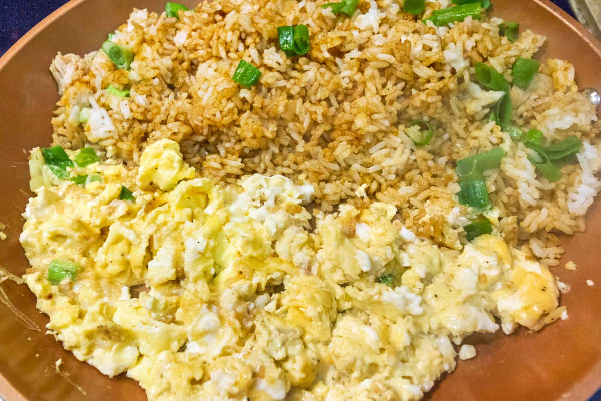 Scrambled eggs in the frying pan with the chicken rice mixture.