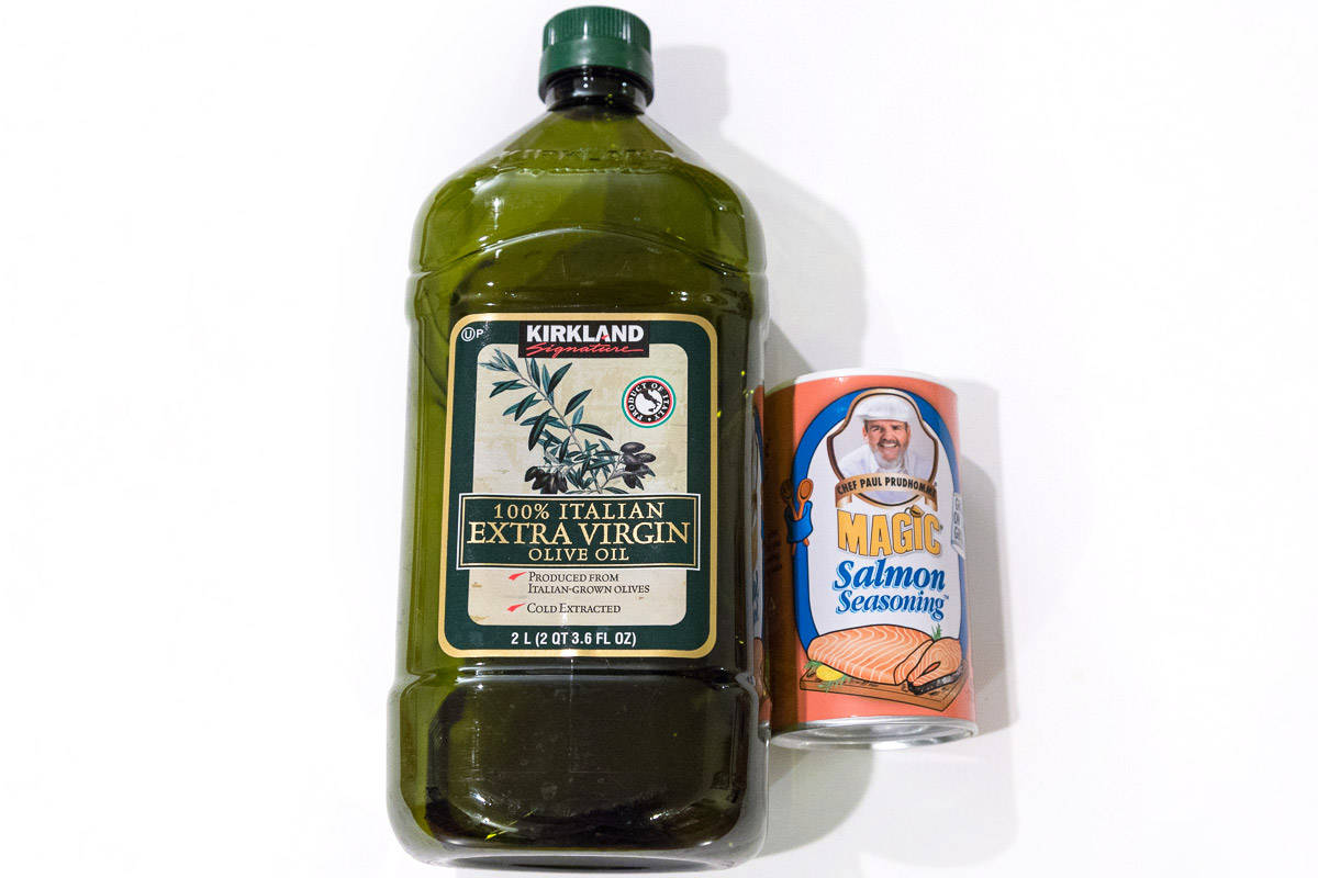 A bottle of extra virgin oil and magic salmon seasoning in a container.